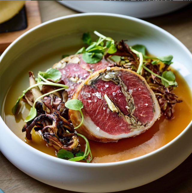 Slices of red meat in a bowl with mushrooms and greens at our Birmingham hotel
